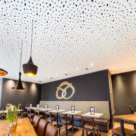 Novinka Knauf Cleneo RE s rozptýleným obdélníkovým děrováním patří k designově nejpůsobivějším typům děrování. V tomto případě je použita na podhledy restauračního zařízení