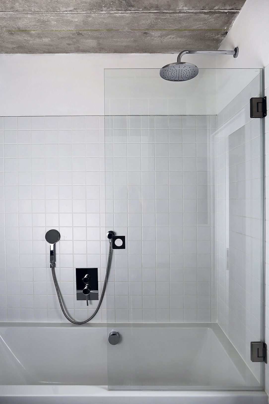 V koupelně je betonový strop kombinovaný s bílými obklady.
