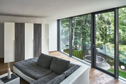 Obývací prostor v horním patře prosklené elementy na výšku místnosti z nichž jeden lze otevírat umožňují maximální přísun světla a výhled do zahrady