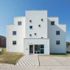 Východní průčelí domu je kvůli objemu schodiště a bytu v nejvyšším patře členitější.