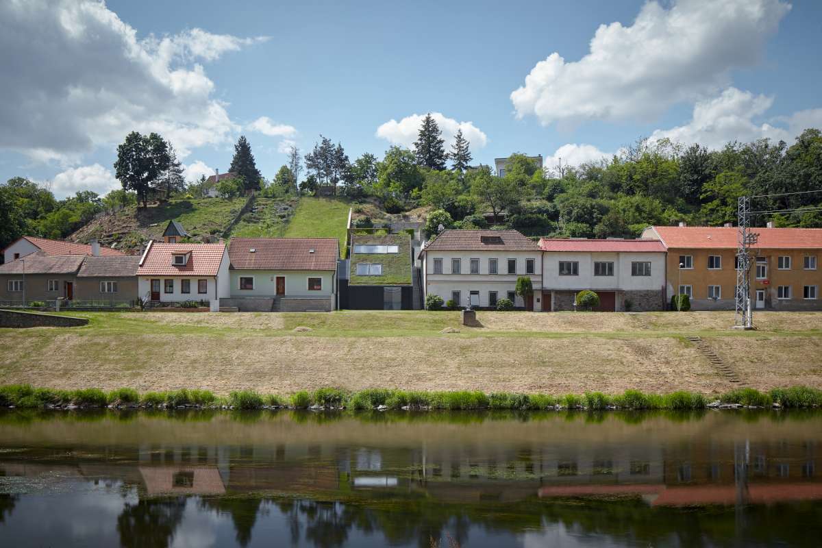 Rodinný dům na nábřeží se zelenou střechou.