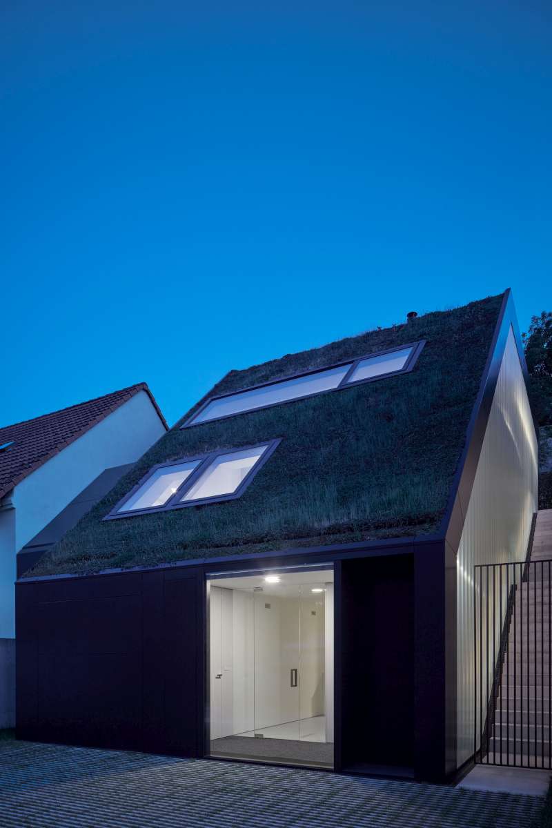 Rodinný dům na nábřeží se zelenou střechou.