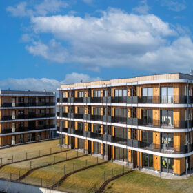 Vícepodlažní dřevostavby Timber Praha s dřevěnou fasádou a moderní architekturou v lokalitě Praha-Řeporyje.
