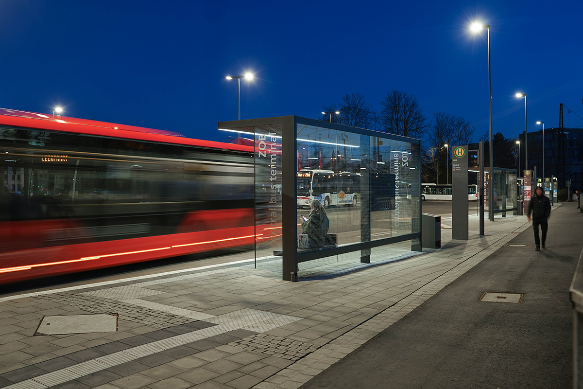 Autobusový terminál s prosklenými přístřešky ve večerním provozu
