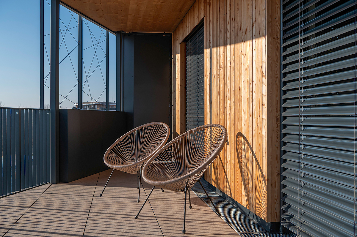 Designový balkon s dřevěným obkladem a venkovním posezením ve dřevostavbě Timber Praha.