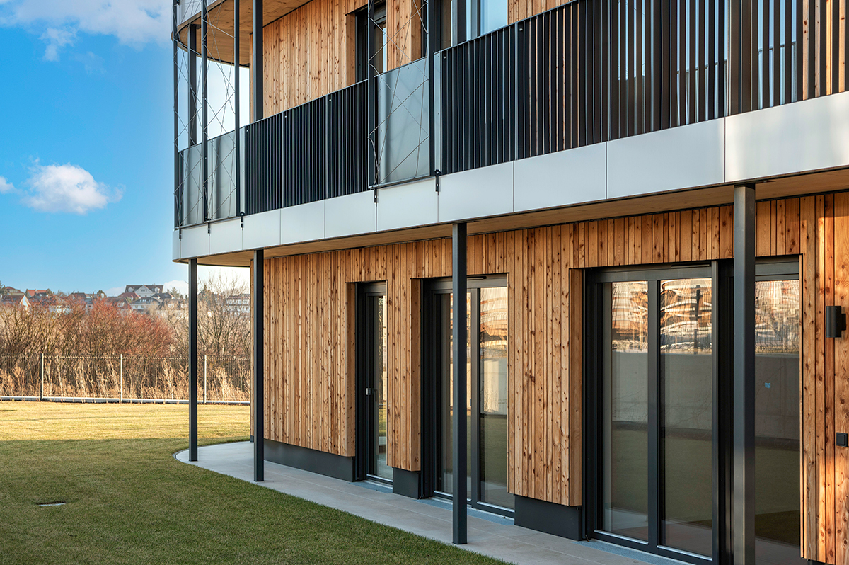 Detailní pohled na přízemí dřevostavby Timber Praha s dřevěnou fasádou a francouzskými okny.