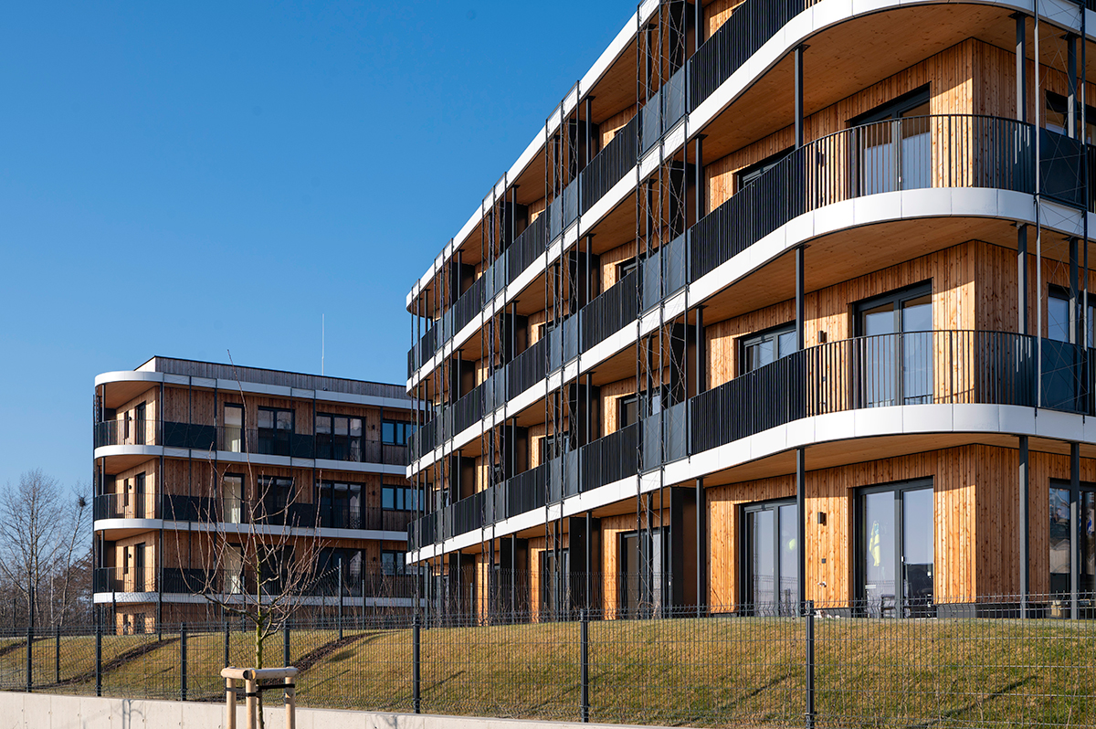 Pohled na moderní dřevostavby Timber Praha s elegantními balkony a ekologickou konstrukcí.