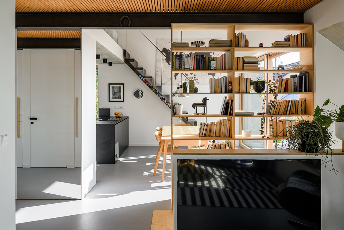 Interiér minimalistického domu s otevřenou kuchyní a vestavěnou knihovnou