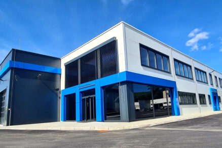 Moderní montovaná ocelová hala AVG s administrativní částí a designovými modrými prvky.