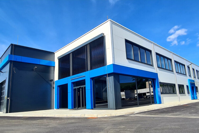 Moderní montovaná ocelová hala AVG s administrativní částí a designovými modrými prvky.
