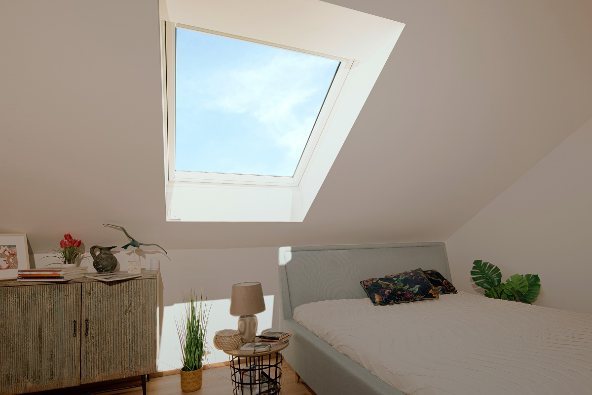 Postel v ložnici pod otevřeným střešním oknem VELUX