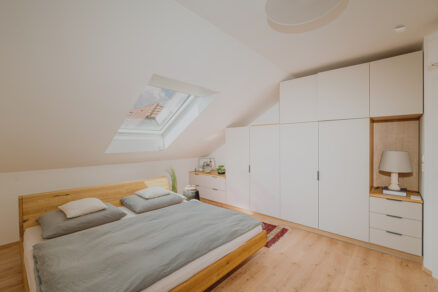 Podkrovní ložnice s moderním střešním oknem VELUX a vestavěným nábytkem