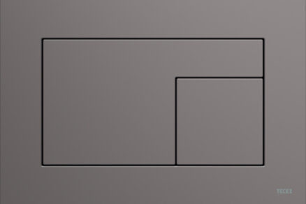 Šedé minimalistické tlačítko pro toaletu na hladkém matném povrchu