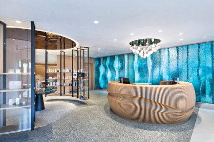Moderní recepce wellness centra s dřevěným pultem a skleněnou stěnou s vodním motivem
