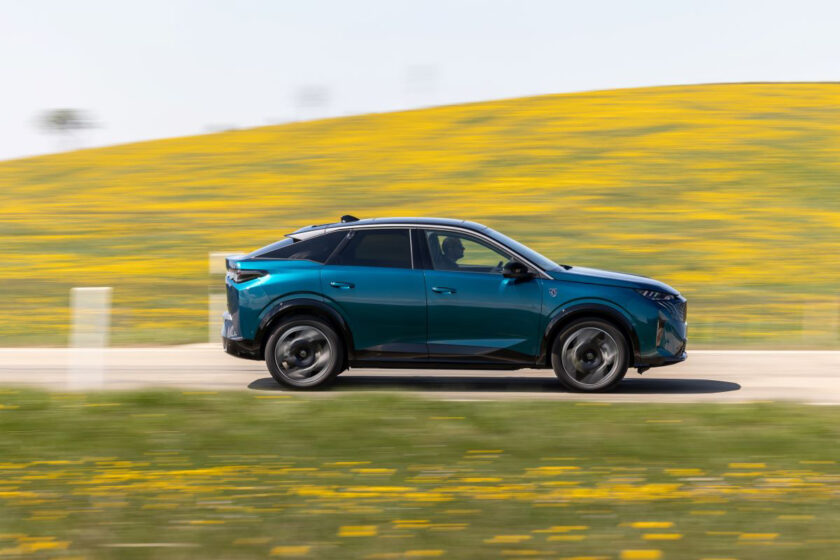 Elektrické SUV Peugeot E-3008 v pohybu na venkovské silnici s květinovým pozadím