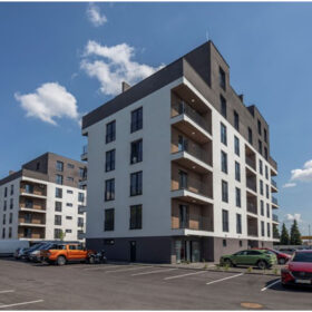 Moderní bytový dům R+R Residence 2 s fasádou v kontrastních barvách a přilehlým parkovištěm