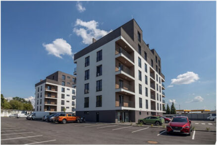 Moderní bytový dům R+R Residence 2 s fasádou v kontrastních barvách a přilehlým parkovištěm