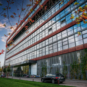 Moderní kancelářská budova s rozsáhlou prosklenou fasádou AVG a prvky udržitelné architektury.