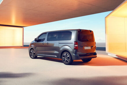 Zadní část vozu Peugeot Traveller zaparkovaného u moderní budovy