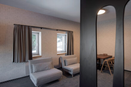 Interiér apartmánu s dvojicou menších okien a závesmi v horskom apartmánovom dome v Špindli