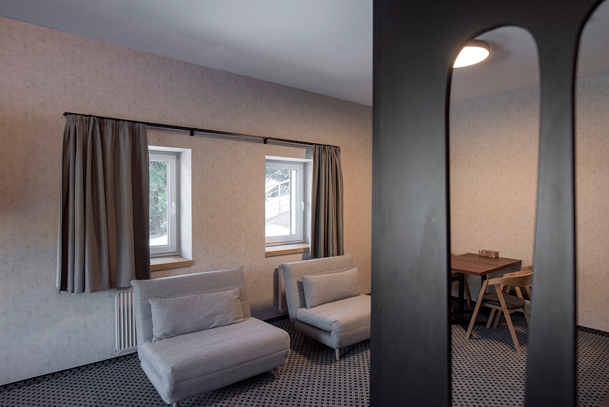 Interiér apartmánu s dvojicou menších okien a závesmi v horskom apartmánovom dome v Špindli