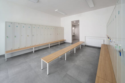 Moderní školní šatna s lavicemi, uzamykatelnými skříňkami a keramickou podlahou
