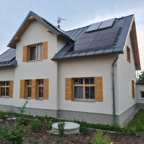 Tradiční rodinný dům s moderní omítkou a dřevěnými akcenty kolem oken