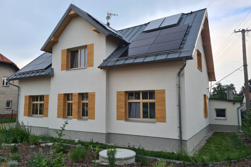 Tradiční rodinný dům s moderní omítkou a dřevěnými akcenty kolem oken