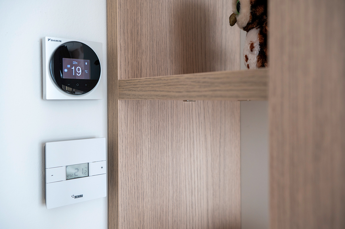 Detailní pohled na nástěnný termostat REHAU a Daikin pro řízení podlahového vytápění