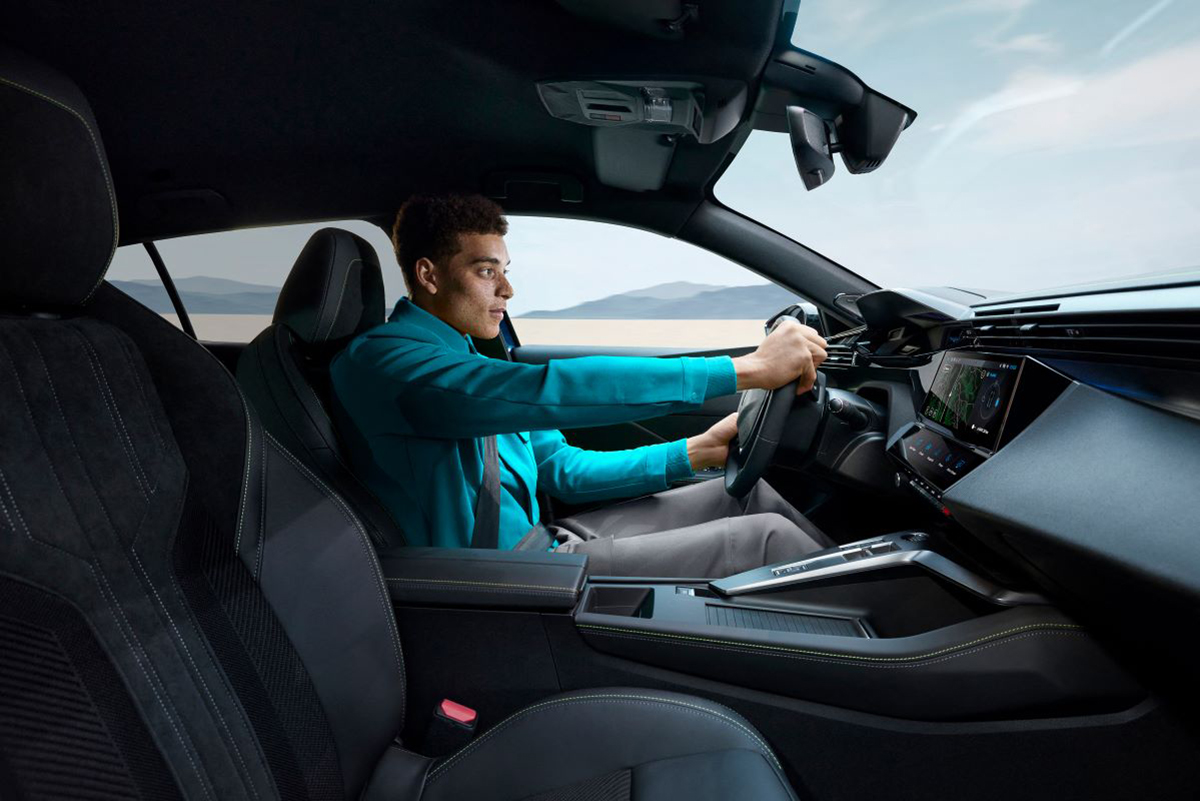 Řidič za volantem vozu Peugeot 408, pohled na kokpit a moderní technologie palubní desky.