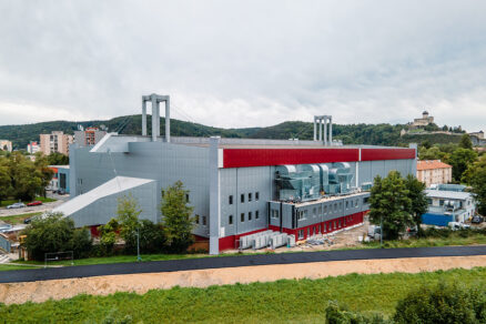 Boční pohled na zimní stadion Pavla Demitry v Trenčíně s výraznými vzduchotechnickými prvky a panoramatem hradu