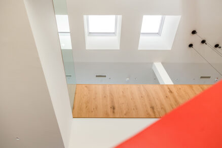 Moderní kancelářský interiér s dřevěnými prvky a světlíky VELUX ve stropě.