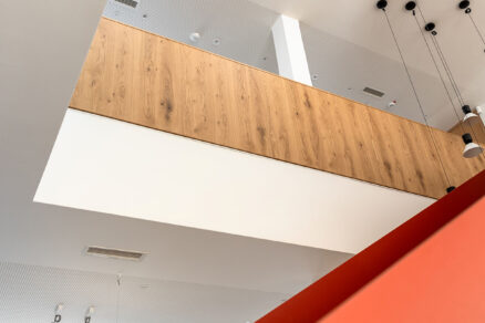 Světlá kancelář s červeným schodištěm a střešními světlíky VELUX.