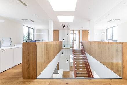 Otevřený pracovní prostor s červeným schodištěm a světlíky VELUX přinášejícími denní světlo.