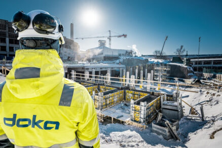 Staveniště v zimních podmínkách s použitím bednění Doka a dohledem pracovníka v ochranném oděvu.
