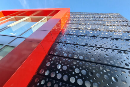 Moderní kovová fasáda z černého děrovaného plechu s výrazným červeným orámováním