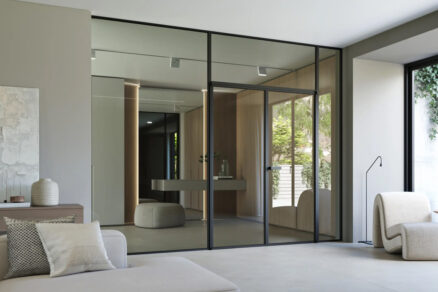 Dvoukřídlé skleněné otočné dveře IDEA s hliníkovým rámem v minimalistickém interiéru