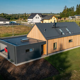 Rodinný dům s dřevěným obkladem a minimalistickou přístavbou s tmavou fasádou