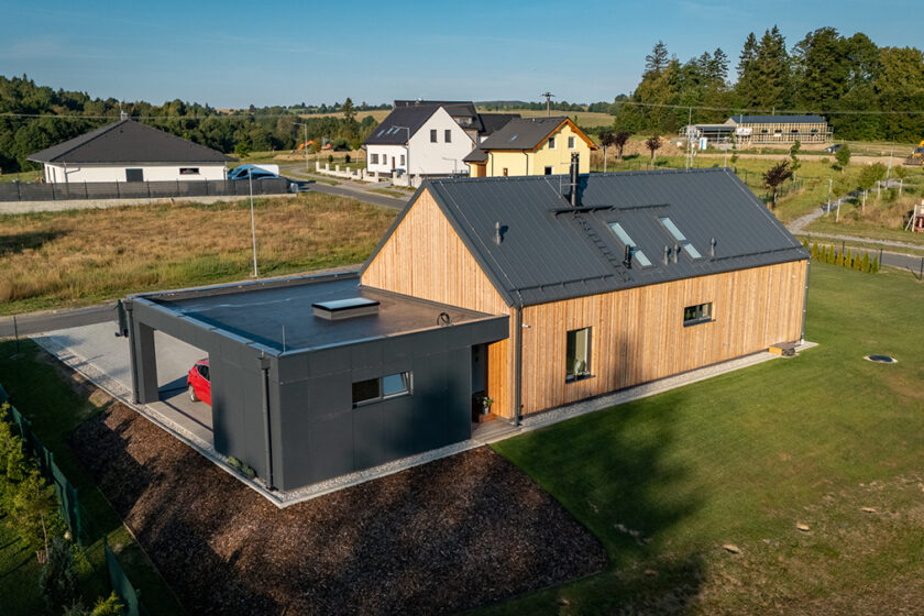 Rodinný dům s dřevěným obkladem a minimalistickou přístavbou s tmavou fasádou