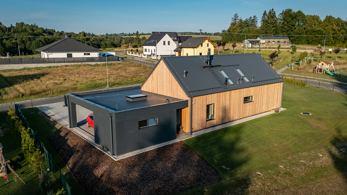 Architektura rodinného domu VESPER HOMES na Jesenicku staví na kontrastu teplého přírodního obkladu z vertikálně kladených dřevěných prken a antracitových ploch fasádních Hardie® Panelů, které chrání přístřešek a rámují hlavní průčelí.