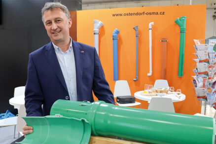 Muž v obleku prezentuje rez plastovým kanalizačním potrubím na výstavním stánku Ostendorf-OSMA