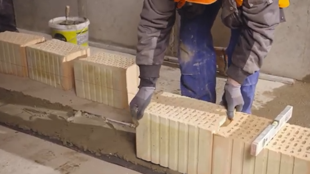 Pokládka první řady - Cihly klademe do maltového lože na sraz bez vzniku mezery ve styčné spáře. Cihly vždy urovnáme poklepem gumovou paličkou a vodováhou zkontrolujeme rovinnost.