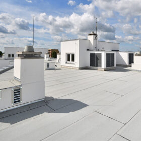 Moderní ploché střechy s bílým hydroizolačním pásem ve městské zástavbě