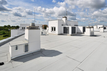 Moderní ploché střechy s bílým hydroizolačním pásem ve městské zástavbě