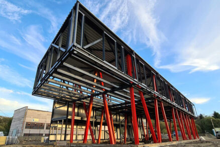 Moderní ocelová konstrukce s červenými nosníky při výstavbě komerční budovy