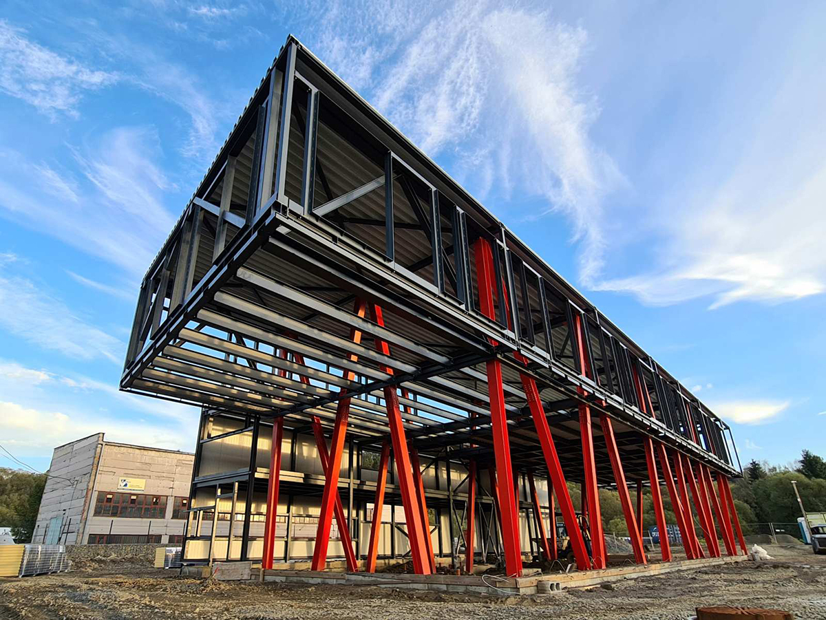 Moderní ocelová konstrukce s červenými nosníky při výstavbě komerční budovy