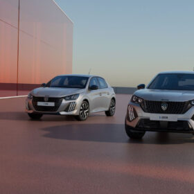 Benzínový Peugeot 208 a elektrický Peugeot e-2008 zaparkované u moderní budovy