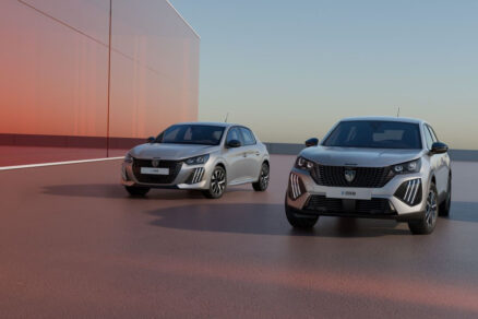 Benzínový Peugeot 208 a elektrický Peugeot e-2008 zaparkované u moderní budovy