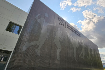 Administrativní budova s perforovanou kovovou fasádou a grafickým motivem.