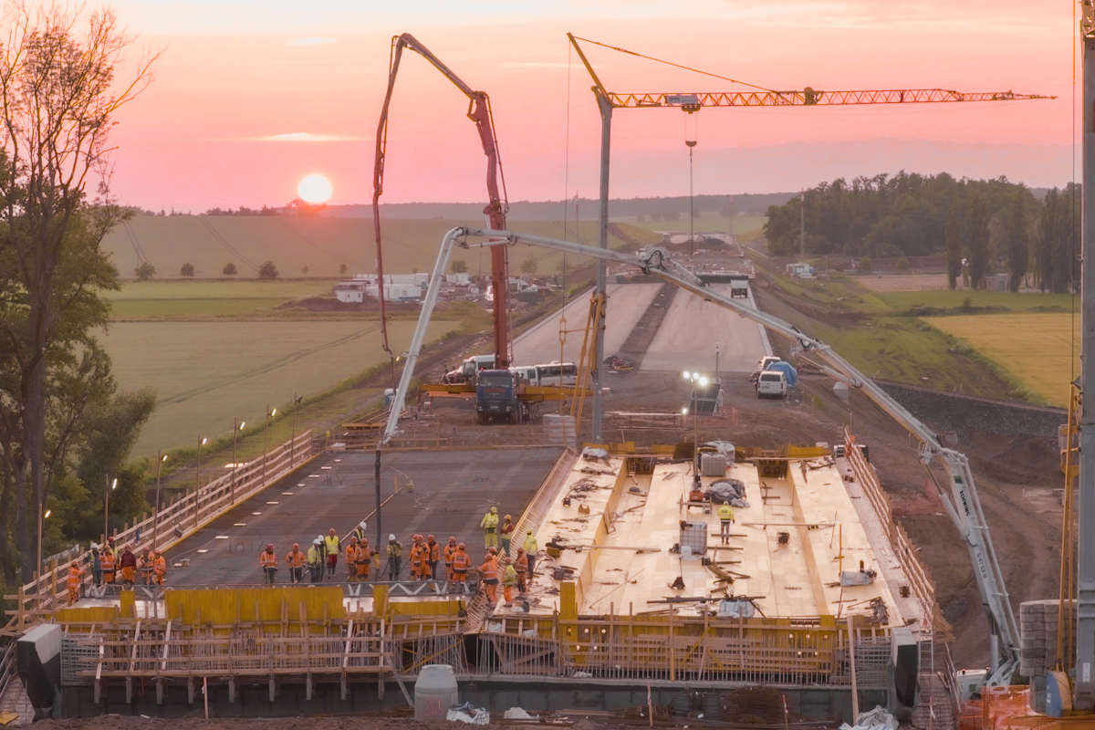 Noční betonáž mostu na dálnici D35 Hořice–Sadová při východu slunce s využitím čerpadel betonu a mrazuvzdorné betonové směsi.